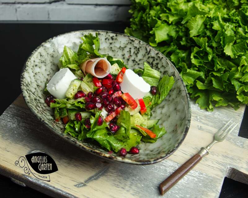 grüner Salat mit Paprika, Ziegenkäse, Parmaschinken und Garanatapfelkernen